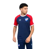 Remera deportiva Umbro del Club Nacional de Football, color azul con mangas rojas y cuello redondo blanco. Presenta el logo de la marca y el escudo del club en el pecho.