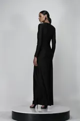 Vestido largo negro de jersey con escote en V profundo, mangas largas, espalda descubierta, abertura lateral en la falda y flecos de cristales en la cintura.