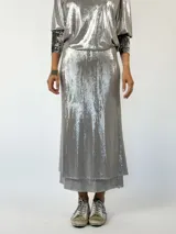 Conjunto plateado brillante de top con breteles finos y pollera larga con efecto mojado.