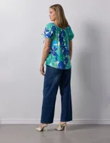 Blusa de seda fría con estampado floral en tonos azules y verdes. Cuello redondo con frunce y mangas cortas amplias con terminación fruncida.