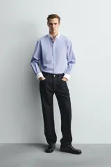 Camisa de corte regular fit confeccionada en tejido ligero de algodón, con diseño de rayas verticales azules y blancas. Presenta cuello abotonado y puños en color blanco a contraste, con cierre frontal de botones.