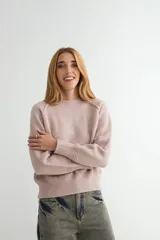 Buzo de tejido de punto en color rosado, con cuello redondo, mangas largas y puños acanalados. Presenta un diseño de tejido texturizado en la parte inferior y en los puños.