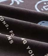 Remera de corte comfort color gris oscuro, con cuello redondo y mangas cortas. Presenta un pequeño estampado frontal con íconos étnicos y lettering en color blanco.