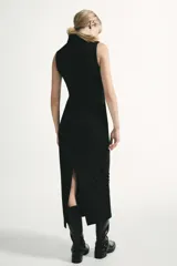 Vestido midi negro con cuello subido y diseño sin mangas (sisa). Presenta un elegante detalle de tejido drapeado en el lateral y cierre trasero con cremallera oculta.