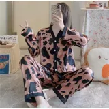 Conjunto de pijama de dos piezas compuesto por una camisa de manga larga con cuello mao y cierre frontal de botones, y un pantalón largo. Presenta un diseño estampado de corazones sobre fondo negro con detalles en color blanco.