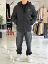 Campera puffer azul marino con capucha ajustable, cierre frontal y bolsillos laterales con cierre a presión. Cuenta con parche redondo con la inscripción "TURK" en el pecho.