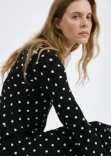 Vestido largo negro con estampado de lunares blancos, de corte recto, escote redondo y mangas largas.