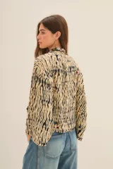 Kimono de corte holgado con estampado animal print tipo tigre, con bordes frontales decorados con pedrería y bordados artesanales. Presenta mangas anchas y forro interior.