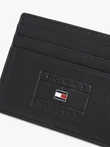 Tarjetero de piel granulada color negro, con múltiples ranuras exteriores para tarjetas y parche frontal con logo en relieve e insignia esmaltada de la marca Tommy Hilfiger.