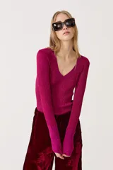 Top fucsia de lurex con escote en V, manga larga y tejido tipo rib.