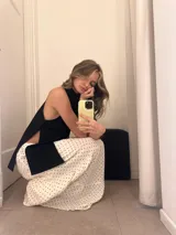 Falda larga de color blanco con estampado de lunares negros, de corte amplio y con volados.