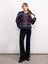 Campera de punto con diseño a cuadros tartán en tonos marrones y beige. Presenta un corte oversize, cierre frontal con cremallera, cuello tipo babero con volados y mangas largas con puños ajustados.