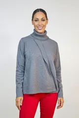 Polerón de cuello alto tejido en color gris, con diseño cruzado en el frente y mangas largas.