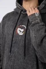 Buzo canguro oversize de algodón friza con efecto de teñido artesanal acid wash en color gris oscuro. Presenta capucha con cordones ajustables, bolsillo frontal tipo canguro y estampa pequeña en el pecho.