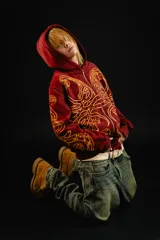 Hoodie con cierre frontal, color bordó, con estampado serigráfico en color dorado que recorre el frente y las mangas con un diseño inspirado en hojas de acanto. Cuenta con bolsillos laterales y cierre metálico.