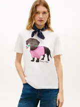 Remera blanca de manga corta y cuello redondo, con estampa en el pecho de un perro salchicha con buzo cuadrillé rosa y flores en la boca.