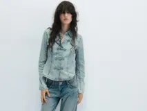 Camisa de denim celeste con cuello solapa, manga larga y cierre frontal con nudos de tela.