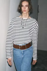 Cinturón ancho de cuero marrón con hebilla cuadrada metálica y apliques de flores metálicas plateadas.