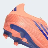 Championes de fútbol Adidas F50 Club, color naranja salmón con tres franjas y detalles en azul oscuro. Cuentan con suela con tapones para césped natural seco y artificial.