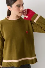 Buzo de lana con cuello redondo, mangas largas con diseño de ochos y puños con abertura para el pulgar. Presenta un diseño tricolor en bloques con franjas en tonos bordó, mostaza y beige.
