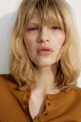 Remera de manga larga color marrón óxido, de tejido acanalado y corte entallado, con cuello redondo y tapeta de botones frontales.