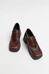 Mocasín de cuero color marrón con suela track negra y tacón bloque.