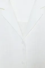 Camisa blanca de lino 100% con cuello solapa de muescas, manga larga y bajo asimétrico. Cierre frontal con botones.