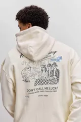 Buzo con capucha y bolsillo tipo canguro, de color crema, con pequeño estampado en el pecho y cordones ajustables en el cuello.