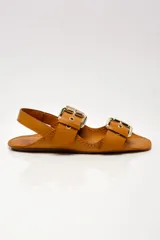 Sandalias de cuero color marrón con dos tiras anchas sobre el empeine, hebillas metálicas doradas y tira trasera.
