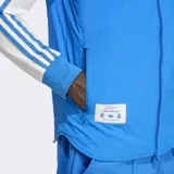 Chaleco azul con cierre frontal, bolsillos con cremallera y diseño reversible. Incluye logo de Adidas y escudo del Real Madrid bordado en el pecho.