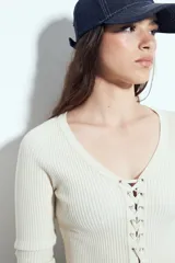 Top de tejido acanalado color negro, con escote en V y cierre frontal mediante cordones ajustables con ojales metálicos. Presenta mangas largas y un corte entallado al cuerpo.