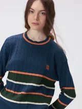 Sweater de punto cable con diseño a rayas horizontales en tonos marrón, amarillo y lila. Presenta cuello redondo acanalado, mangas largas con puños a juego y logo bordado en el pecho.