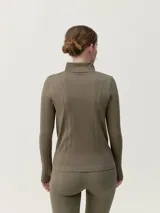 Chaqueta entallada de tejido técnico con cierre frontal completo, cuello alto y mangas largas con aberturas para pulgares. Presenta un diseño de texturas acanaladas verticales.