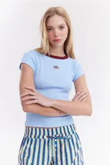 Top de canalé amarillo con cuello redondo y ribetes en color bordo, mangas cortas y detalle de logo bordado en el pecho.