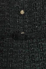 Chaleco de tejido tipo tweed en color negro, con cuello redondo y cierre frontal de botones dorados. Presenta un diseño entallado con cinturón integrado del mismo tejido y bajo con pliegues.