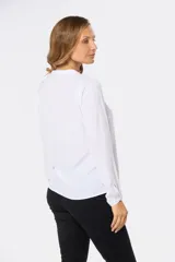 Blusa de manga larga en color azul marino, con escote en V y diseño de doble capa en el frente. Presenta puños elásticos y un pequeño aplique metálico decorativo en el ruedo.