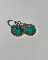 Aros colgantes dorados con dije circular de resina color turquesa, bordeado con strass. El arito es de acero quirúrgico.
