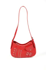 Cartera tipo baguette de color rojo con acabado brillante, decorada con múltiples cierres metálicos, ojales y dos pequeñas hebillas decorativas en el frente. Incluye un bolsillo pequeño con solapa y cierre de botón a presión, además de una correa larga ajustable.
