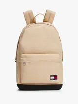 Mochila Tommy Jeans de diseño redondeado en color beige con base negra. Cuenta con compartimento principal con cierre de cremallera, bolsillo frontal con cierre, correas ajustables acolchadas y asa superior. Incluye parche distintivo de la marca en la parte frontal.