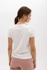 Remera blanca de algodón con estampado de dos flores en tonos pastel y logo de la marca en cursiva. Corte clásico y cuello redondo.