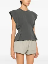 Remera sin mangas gris oscura, de corte minimalista y estructurado, con hombreras marcadas y pliegues laterales ajustables que moldean la silueta.