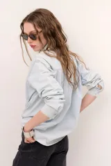 Camisa de jean de corte oversize, color celeste claro, con cierre frontal de broches metálicos y un bolsillo aplicado en el pecho.