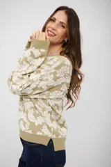 Buzo de tejido de punto con diseño floral en tonos beige y crema, de corte holgado, cuello redondo y mangas largas con puños acanalados.