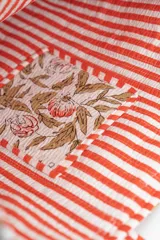 Bolso tipo tote bag de tela acolchada con estampado floral en tonos gris y blanco. Presenta asas largas reforzadas con detalle de rayas en los bordes.