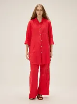 Camisa de lino de silueta relajada y largo irregular, color rojo, con mangas tres cuartos terminadas en volados y cierre frontal de botones a contratono.