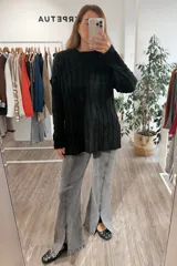 Sweater de punto negro con diseño de trenzas verticales, cuello redondo y corte holgado con aberturas laterales en el ruedo.
