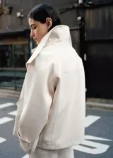 Parka de corte recto color blanco, confeccionada en mezcla de lana, con cuello embudo, bolsillos de solapa laterales, manga larga con trabillas y cierre delantero con botones.