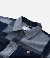 Campera de jacquard de algodón con diseño patchwork de cuadros en tonos azules. Presenta cuello inglés, cierre frontal con botones metálicos, mangas largas y bolsillos delanteros.