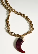Collar largo dorado con cadena de eslabones gruesos y dije colgante en forma de cuerno de resina color bordó.
