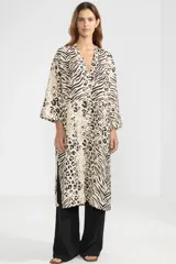 Camisa larga de lino color crema con estampado animal print que combina patrones de leopardo y cebra, cuello en V, cierre frontal con botones y mangas tres cuartos.